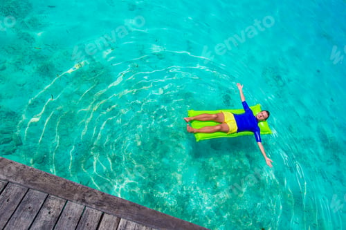 Preview: Young happy man relaxing on inflatable mattress in the sea