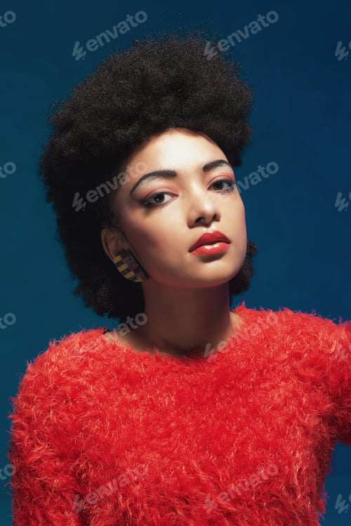 Preview: Close Up Gorgeous Young African American Woman In Fuzzy Red Tops Staring At The Camera Against Blue