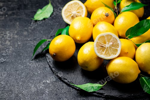 Preview: Juicy lemons with leaves on a stone board.