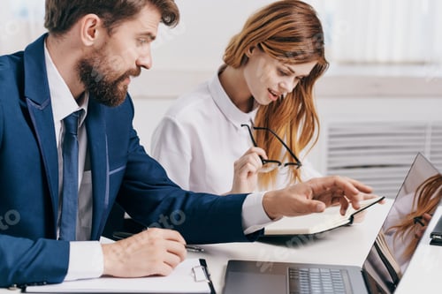 Preview: business man and woman sitting at the table in front of laptop team technology