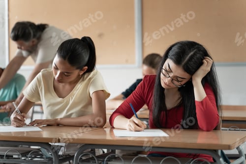 Preview: Latin and Hispanic Female Students writing exam in the college high school classroom