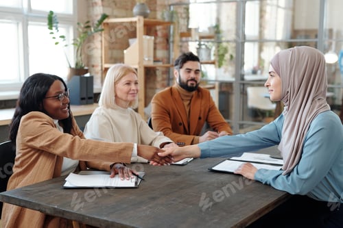 Preview: Happy African businesswoman shaking hand of Muslim female applicant