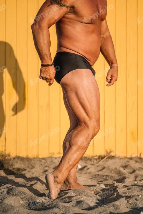 Preview: Muscular crop older man poses yellow background.