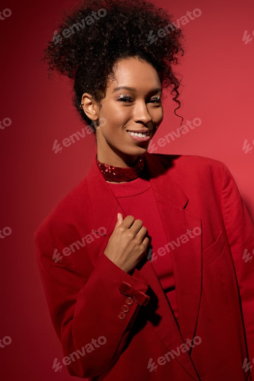 Preview: Young woman radiates joy in vibrant red outfit against a bold backdrop
