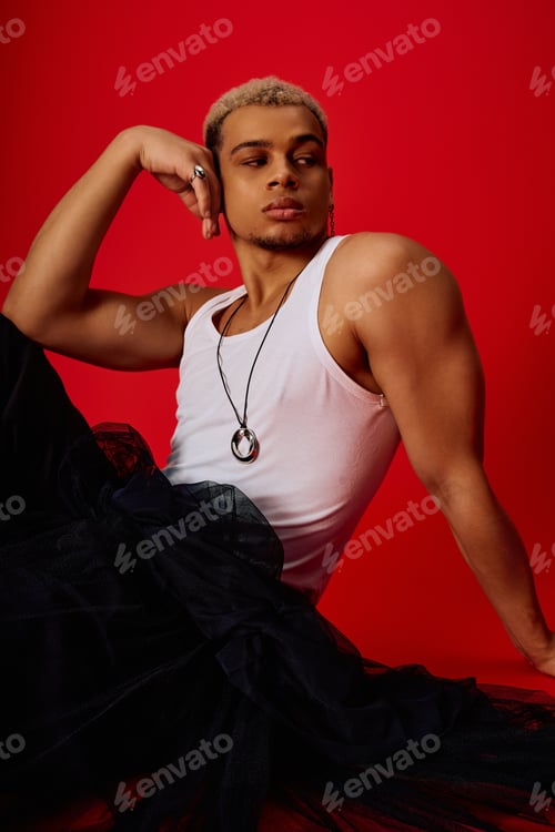 Preview: Young African American man showcases bold style in trendy red studio setting