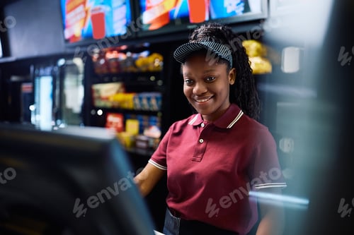 Preview: Happy black concession stand worker using computer in movie theater.