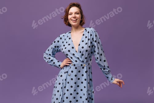 Preview: Young lady in dress posing at studio. Joyful lady with dark hair, nude makeup and polka dot outfit,