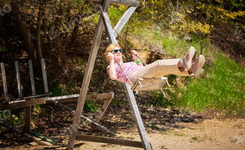 Preview: Senior woman joyfully swinging on a swing and having fan