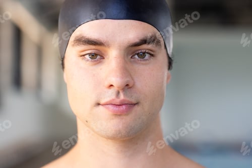 Preview: Caucasian boy with brown hair, green eyes in black cap stands indoors near water