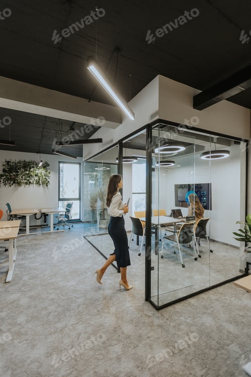Preview: Young woman with digital tablet walking in the modern office