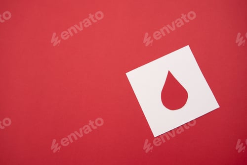 Preview: White paper cutout of a blood drop on a red background, blood donation and healthcare concept