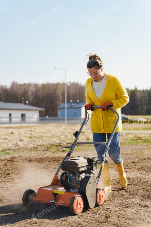 Preview: Woman villager is using aerator machine to scarification and aeration of lawn or meadow
