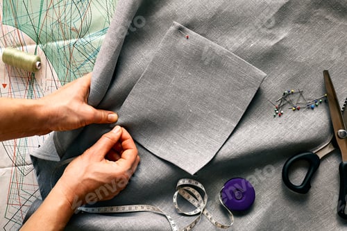 Preview: Woman sketching pattern on a linen fabric. Seamstress basting and sewing in a small studio