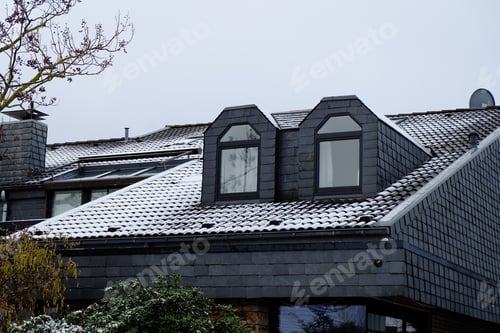 Preview: Roof of a building with two dormers under a cloudy sky in winter