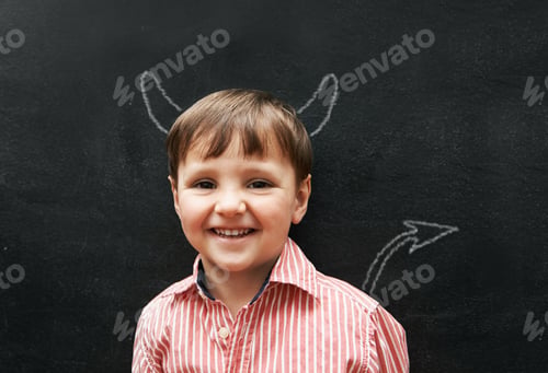 Preview: Stuido portrait of a young boy with chalk-drawing horns and tail behind him