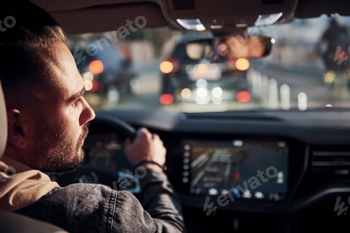Preview: Rear view of handsome unshaved man in fashionable clothes that riding his automobile