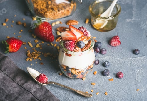 Preview: Yogurt oat granola with fresh berries, nuts, honey and mint leaves in glass jar