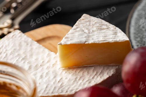 Preview: Cheese served with grapes and honey on grey surface