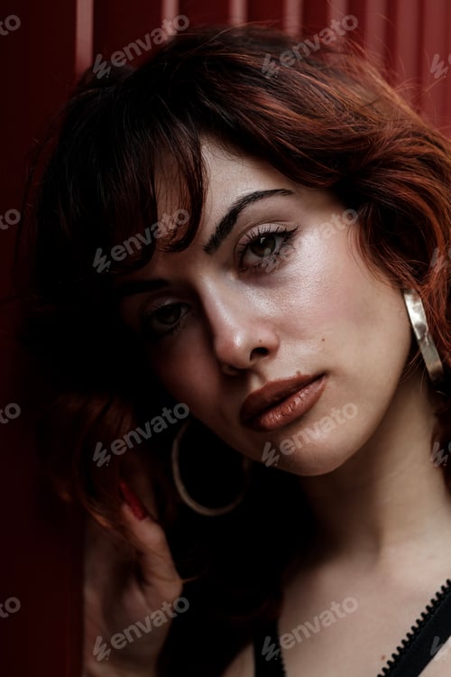 Preview: Close portrait of young red hair woman leaning on red metallic wall.