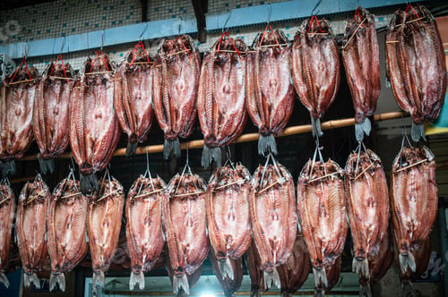 Preview: Busy market, showing a variety of preserved fish hanging from a large industrial roof