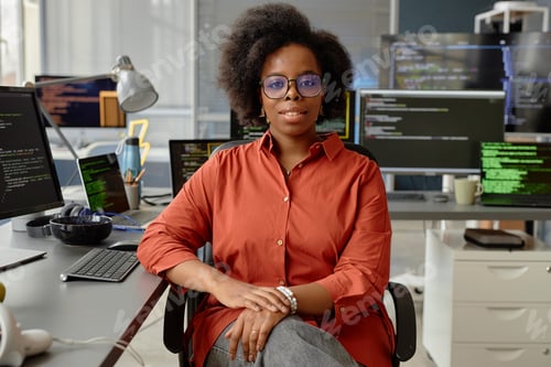 Preview: Female Software Developer in Orange Shirt at Desk