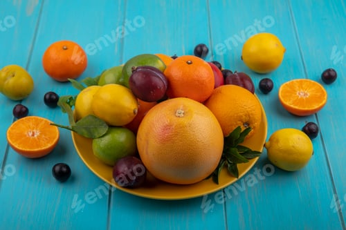 Preview: side view fruit mix on a plate oranges cherry plums grapefruit lemons limes and plums on a turquoise