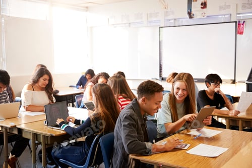 Preview: Wide Angle View Of High School Students Sitting At Desks In Classroom Using Laptops