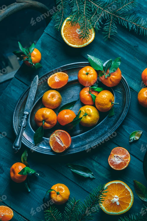 Preview: Tangerines with green leaves on a green wooden table in a rustic style surrounded by spruce branches