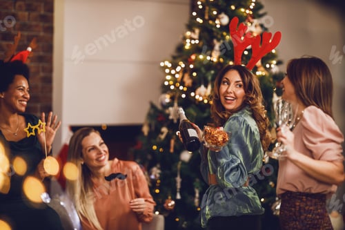 Preview: Four Multiethnic Female Friends Having Fun And Make Toast As They Celebrate At Home Christmas Party