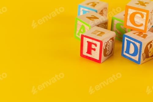 Preview: Colorful wooden blocks with letters on a yellow color background