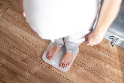 Preview: Close up pregnant woman standing on scales at home View from above