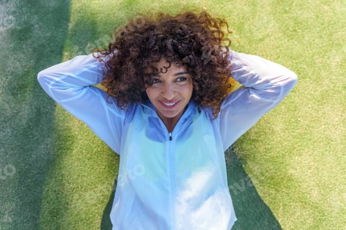 Preview: Young smiling woman performing crunches on green sports field, enjoying outdoor fitness workout