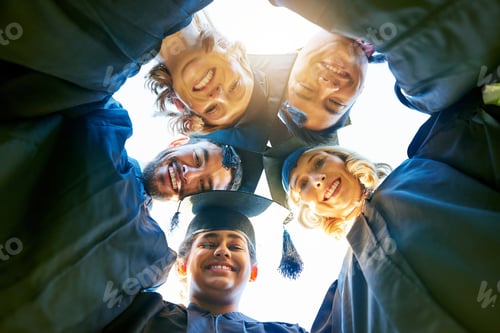 Preview: Portrait of a group of students standing in a huddle with their heads together on graduation day