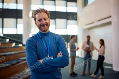 Preview: Confident business seminar presents in convention center looking at camera.