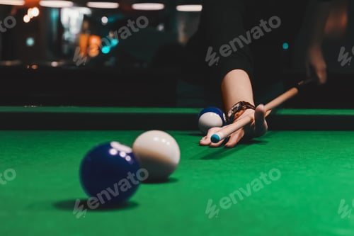 Preview: Player holding que and aiming to billiard white ball. White ball on gree poll table.