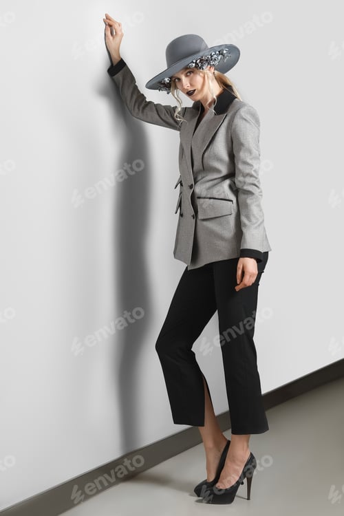Preview: Pretty fashion model in jacket, pants and broad-brim hat with flowers