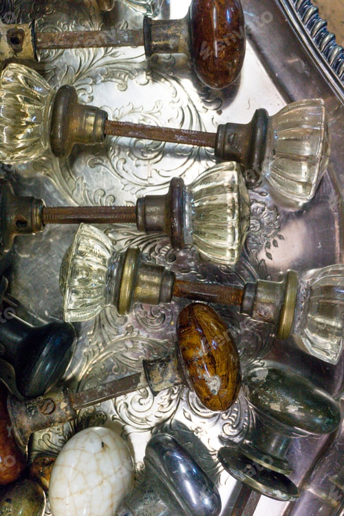 Preview: Overhead view with variety of antique doorknobs on silver tray