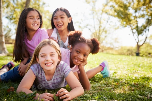 Preview: Four schoolgirls lying on each other in a field, laughing