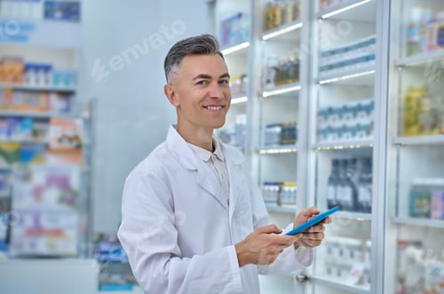 Preview: Druggist with a tablet computer smiling at the camera