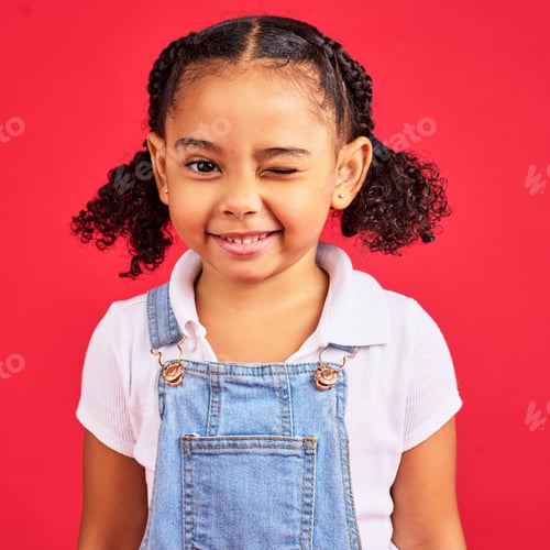 Preview: Portrait, wink and a black child on a red background in studio having fun or feeling carefree. Kids