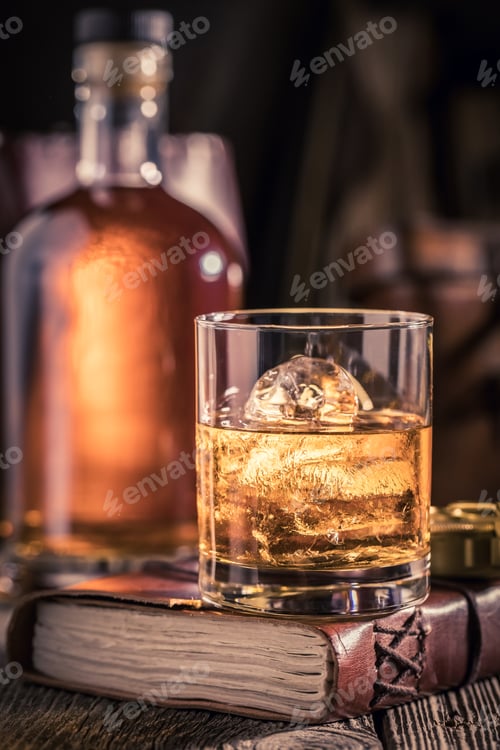 Preview: Glass of whisky with ice on old journal