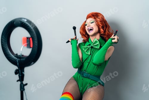 Preview: Happy drag queen social influencer vlogging online a makeup class with smartphone cam and ring led