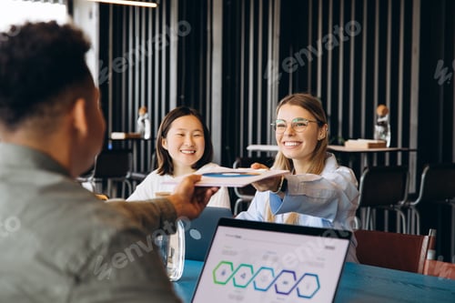 Preview: Businesswomen receiving documents during corporate meeting in modern office