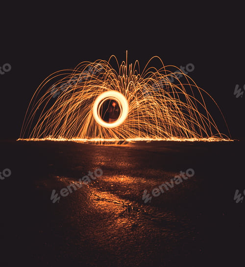 Preview: Man creating rotating and swirling sparks in a dark place and on the wet surface