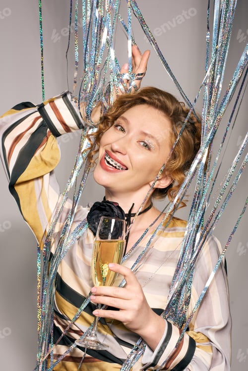 Preview: Joyful young woman delightfully wrapping gifts with shimmering ribbons and festive decorations