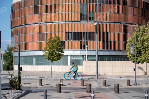 Preview: Business woman in green suit and helmet riding bicycle on the street