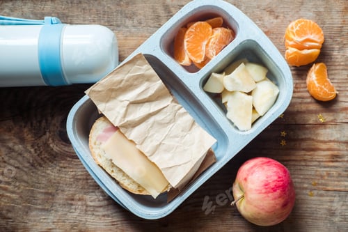 Preview: schoolboy lunch box with thermos on wooden background.apple,tangerine,sandwich in lunchbox