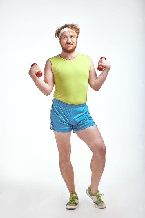 Preview: Red haired, bearded, plump man is holding the dumbbells