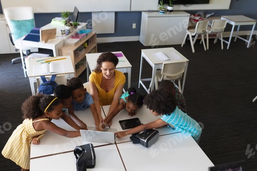 Preview: Young female caucasian teacher showing laptop to african american elementary students in class