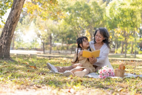 Preview: Child and Senior Reading Book in the Park